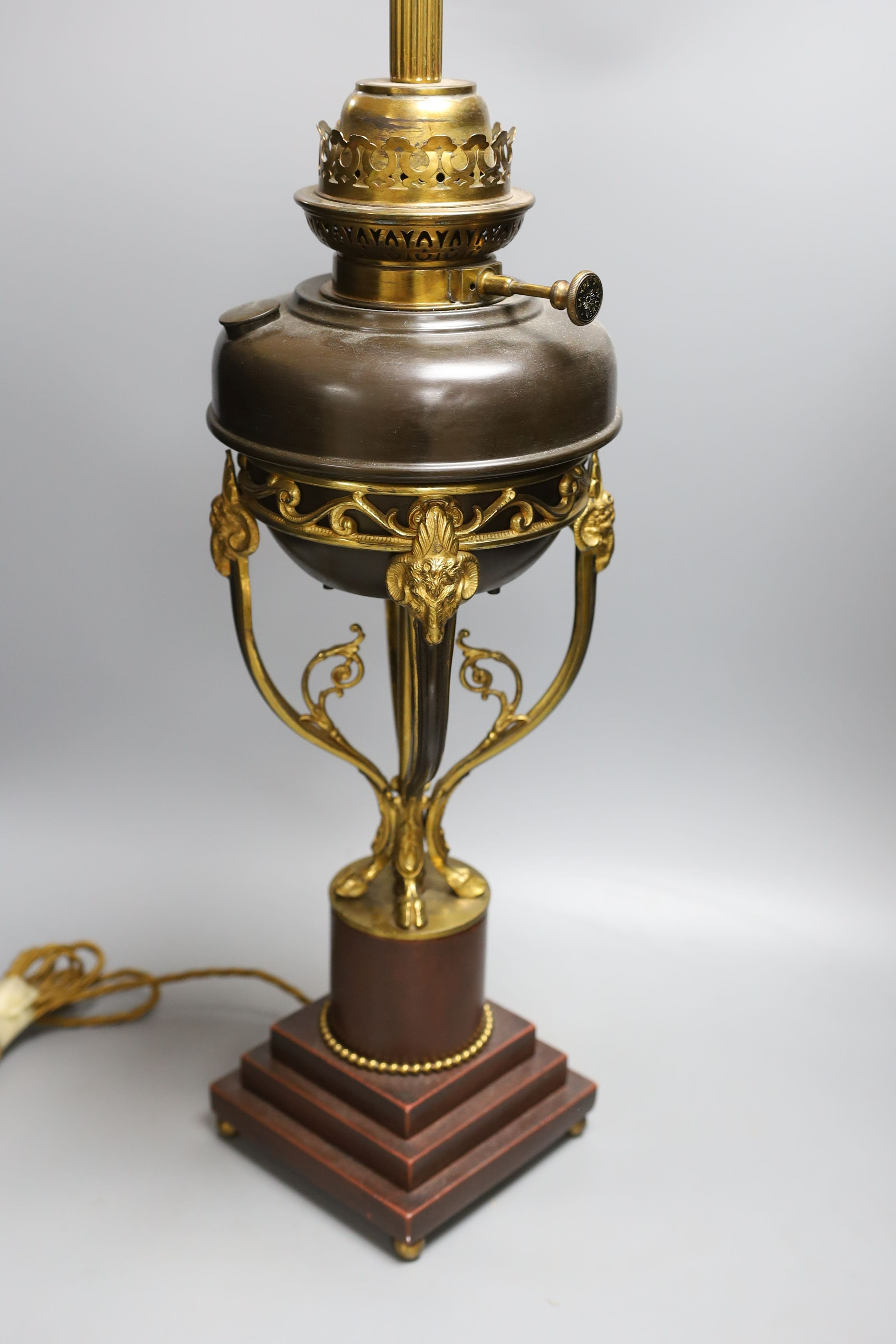 A gilt metal ‘rams head and hoof’ monopodia oil lamp, converted to electric, total height 72cm